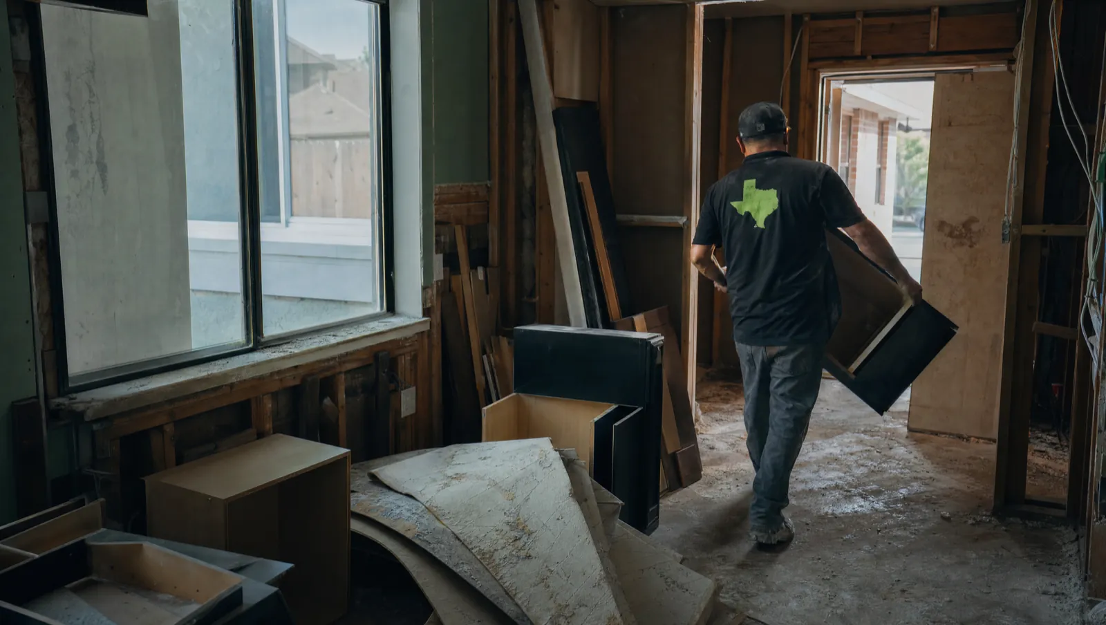Interior demolition in progress in a Waco, Texas home — cabinets pulled out and drywall stripped to the studs